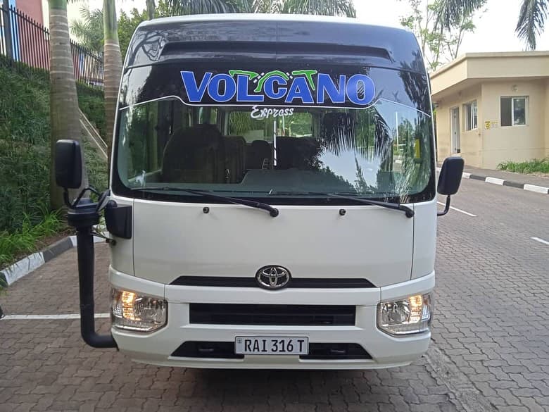 A white Volcano Express Toyota Coaster parked at the depot